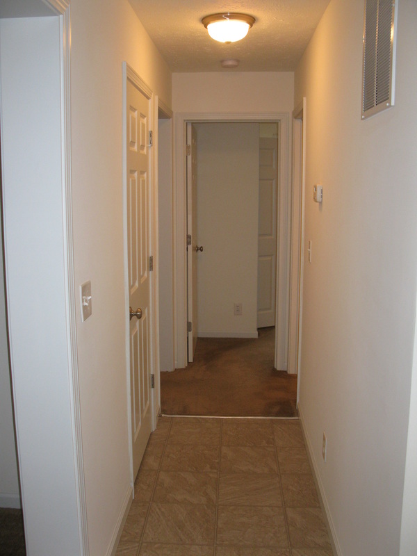 View down hallway in College Park Duplex. door to the basement is on the first left, the master bedroom is on the second left, the second bedroom is straight ahead, and the bathroom is on the right