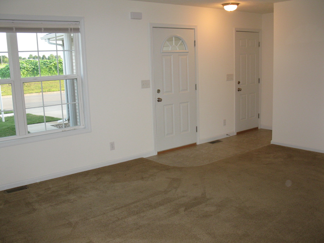 Living room looking towards the front door with garage door to the right in College Park Duplex